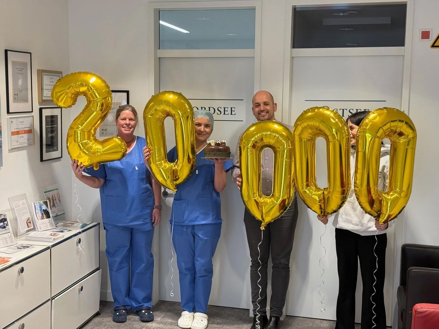 Unser Team feiert 20.000 Operationen mit goldenen Luftballons und Torte